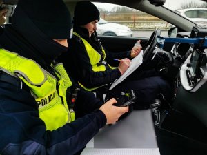 Dwóch policjantów siedzących w radiowozie.