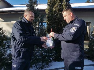 Komendant Miejski Policji w Białymstoku przekazuje kartki z życzeniami i upominki policjantowi.