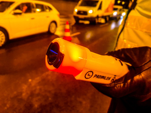 Policjant trzymający urządzenie do badania trzeźwości z czerwoną lampką.