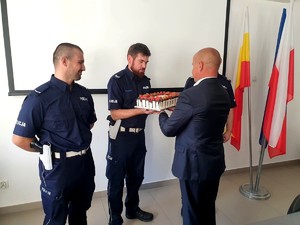 Mężczyzna wręczający policjantom tort