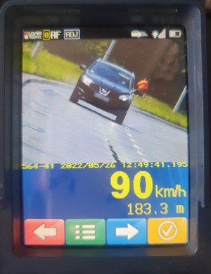 Monitor urządzenia do pomiaru prędkości, na nim widoczny pojazd oraz prędkość 90 kilometrów na godzinę.