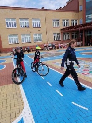 Policjantka idąca przed dwójką rowerzystów