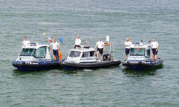 Trzy łodzie policyjne, a na nich stojący policjanci.