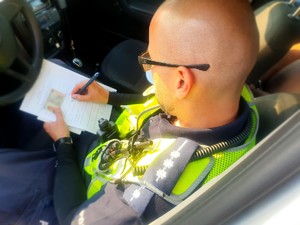 Policjant wypełniający w radiowozie dokumentację