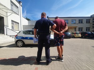Policjant trzymający zatrzymanego mężczyznę.
