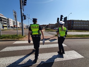 Policjanci idący przez przejście dla pieszych.