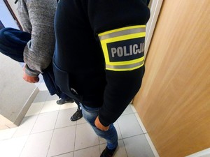 Policjant stojący bokiem obok zatrzymanego