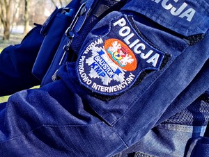 Ujęcie ramienia policjanta a na niej naszywka z napisem Wydział Patroloow-Interwencyjny Komendy Miejskiej Policji w Białymstoku