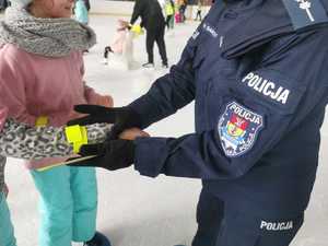 Policjantka zakłada odblask na rękaw dziecka.
