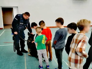 Policjant z psem służbowym stojący obok dzieci.