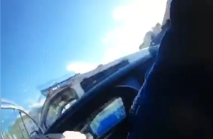 Ręka policjanta przy samochodzie, w tle radiowóz.