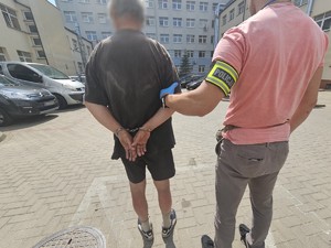 Policjant trzyma zatrzymanego mężczyznę.