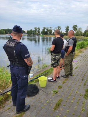 Policjant stojący nad wodą z trzema mężczyznami