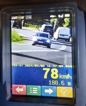 Ekran urządzenia do pomiaru prędkości w wynikiem i mierzonym samochodem.