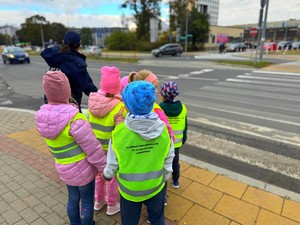 Policjantki w terenie z przedszkolakami ćwiczą przechodzenie przez przejście dla pieszych.