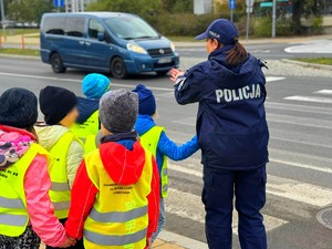 Policjantki w terenie z przedszkolakami ćwiczą przechodzenie przez przejście dla pieszych.