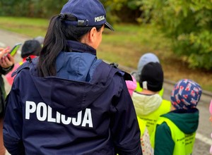 Policjantki w terenie z przedszkolakami ćwiczą przechodzenie przez przejście dla pieszych.