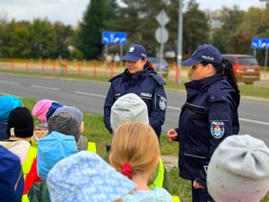 Policjantki w terenie z przedszkolakami ćwiczą przechodzenie przez przejście dla pieszych.