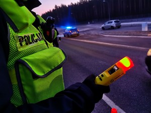 Policjant trzymający w ręku urządzenie do badania stanu trzeźwości