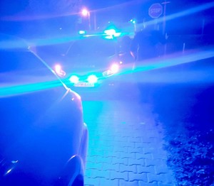 radiowóz z włączonymi sygnałami świetlnymi i zatrzymany pojazd