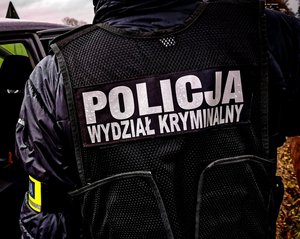 Plecy policjanta w kamizelce z napisem policja wydział kryminalny