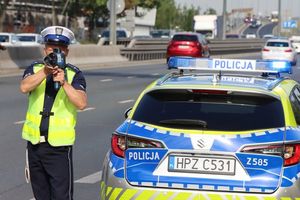 Policjant przy radiowozie mierzy prędkość