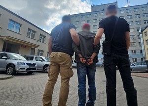 Policjanci trzymają zatrzymanego mężczyznę