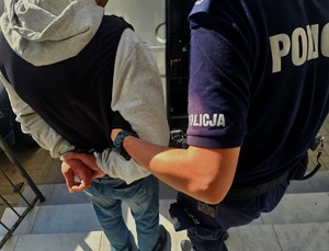 policjant wprowadza zatrzymanego mężczyznę do samochodu