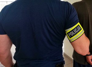 Policjant trzyma zatrzymanego mężczyznę