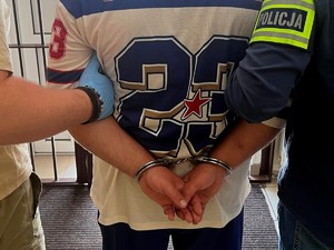 policjanci trzymają mężczyznę w kajdankach
