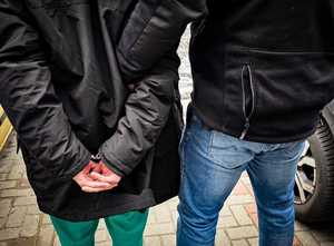 Policjant trzyma zatrzymanego mężczyznę