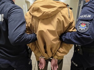 Policjanci prowadzą zatrzymanego mężczyznę