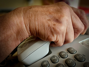 ręka trzymająca słuchawkę telefonu stacjonarnego