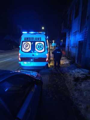 Karetka, obok stojący policjant