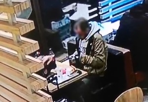 Zrzut z monitoringu mężczyzny siedzącego przy stoliku