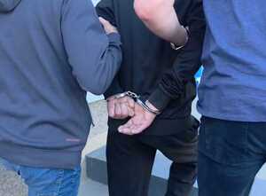 Policjanci prowadzą zatrzymanego mężczyznę