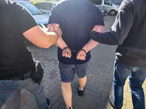 Policjanci prowadzą zatrzymanego mężczyznę