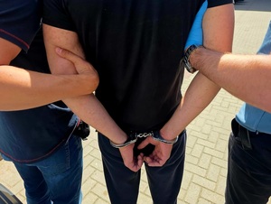Policjanci trzymają zatrzymanego mężczyznę