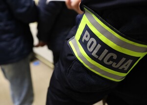 opaska na ręku policjanta z napisem policja