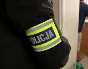 rękaw policjanta z opaską z napisem policja