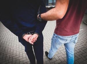 policjant prowadzi zatrzymanego mężczyznę